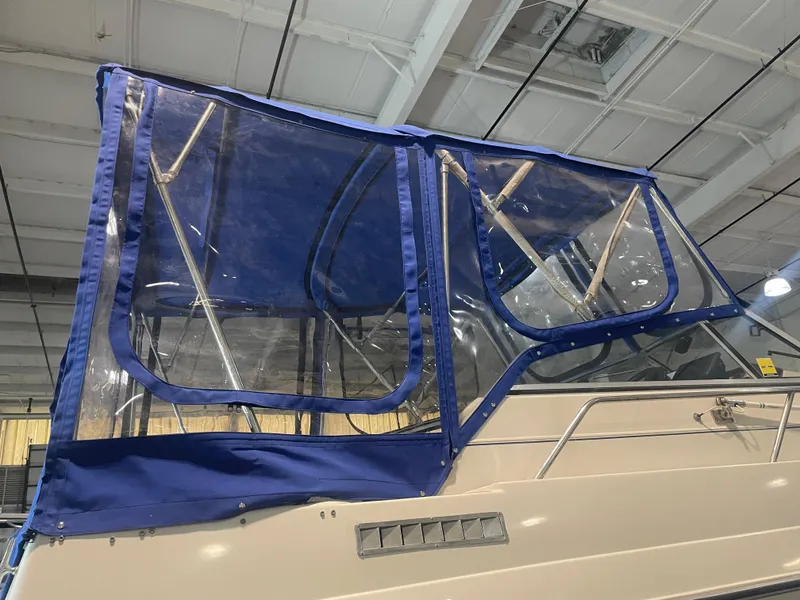 Slide: The Image of 1993 Regal Ambassador 233 boat with blue canvas enclosure in a warehouse setting. - 14