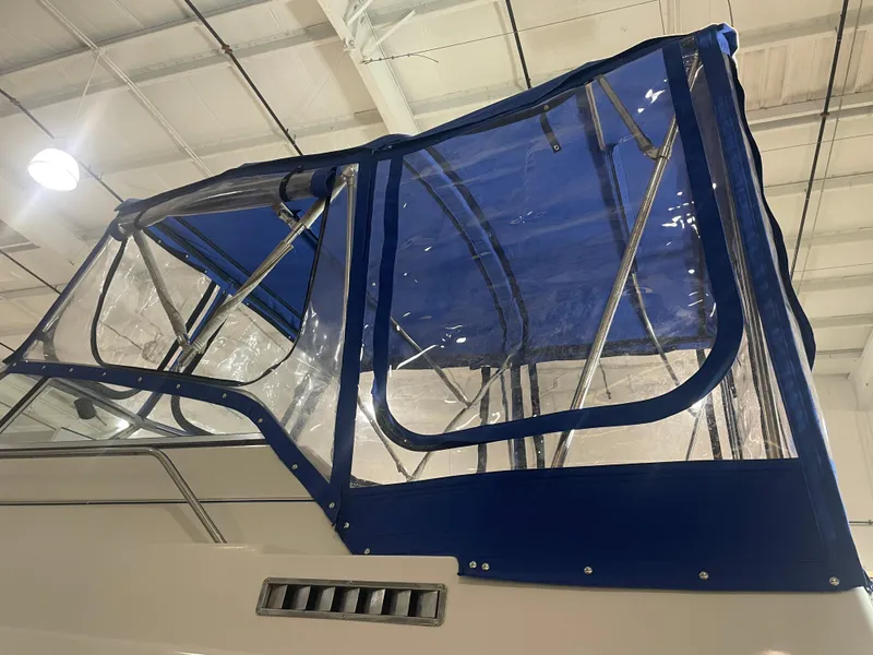 Slide: The Image of 1993 Regal Ambassador 233 boat with blue canopy in a warehouse setting. - 16