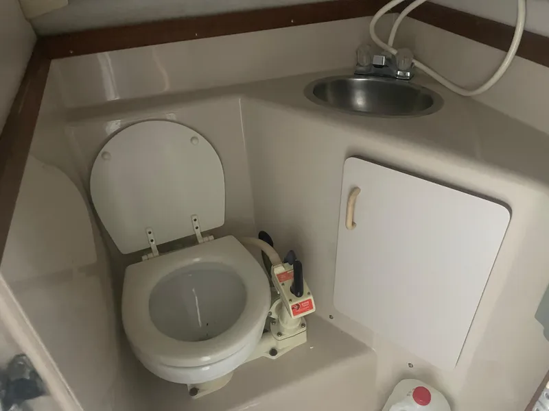 Slide: The Image of 1993 Regal Ambassador 233 boat bathroom with toilet, sink, and storage cabinet. - 32