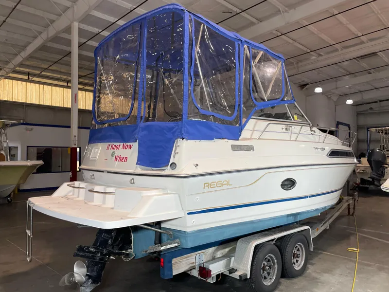 Slide: The Image of 1993 Regal Ambassador 233 boat with blue canopy on trailer in indoor storage. - 4