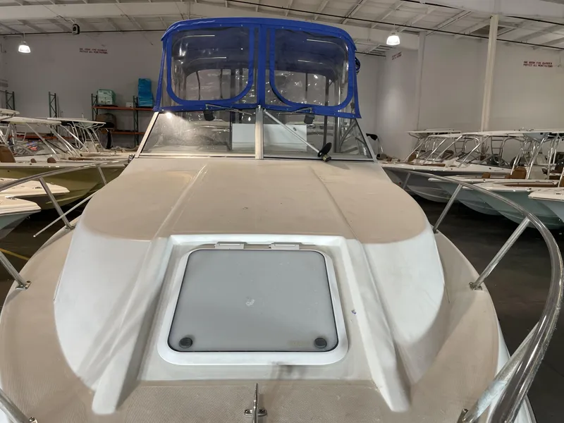 Slide: The Image of 1993 Regal Ambassador 233 boat in indoor storage, featuring a blue canopy. - 5