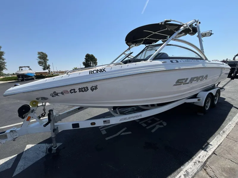 Slide: The Image of 2009 Supra Launch 24 SSV boat on trailer, parked outdoors under clear sky. - 1
