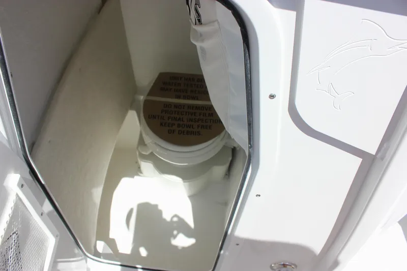 Slide: The Image of Interior of 2026 Sea Hunt Ultra 245 SE boat, featuring a compact marine toilet. - 16