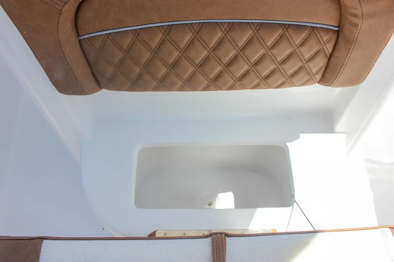 Slide: The Image of 2026 Sea Hunt Ultra 245 SE boat interior with brown quilted seating and storage compartment. - 21