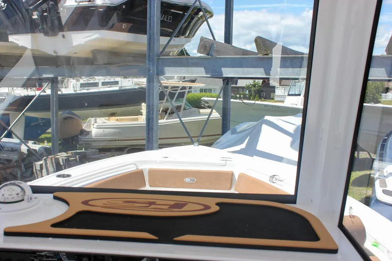 Slide: The Image of 2026 Sea Hunt Ultra 245 SE boat interior view with docked vessels in background. - 25