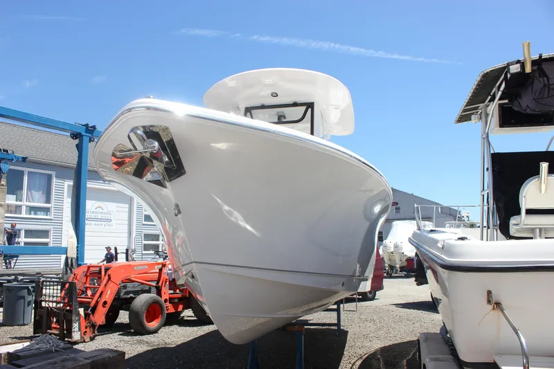 Slide: The Image of 2026 Sea Hunt Ultra 245 SE boat in a marina, front view under clear blue sky. - 37