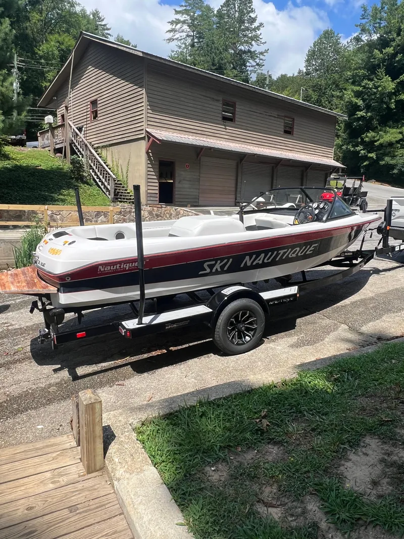 Slide: The Image of 1997 Correct Craft Ski Nautique 196 boat on trailer, parked near a wooden building. - 8