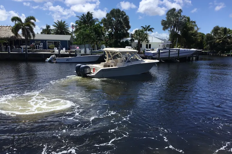 The Image of 2022 Grady-White Freedom 325 boat cruising on a sunny waterfront with palm trees. - 5