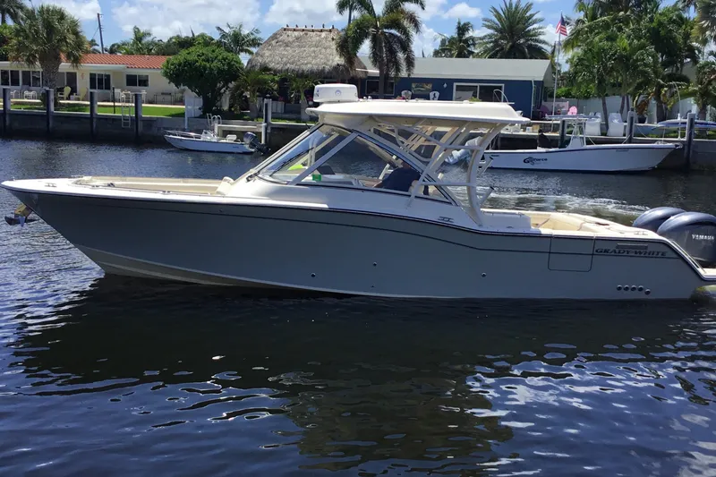 Slide: The Image of 2022 Grady-White Freedom 325 boat on a sunny waterfront with palm trees. - 18