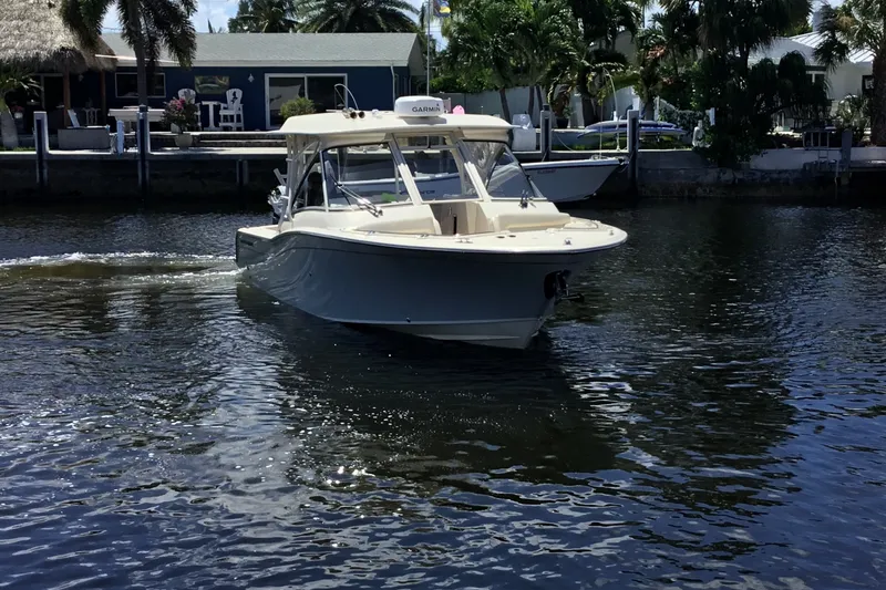 Slide: The Image of 2022 Grady-White Freedom 325 boat cruising on a calm waterway, surrounded by lush greenery. - 14