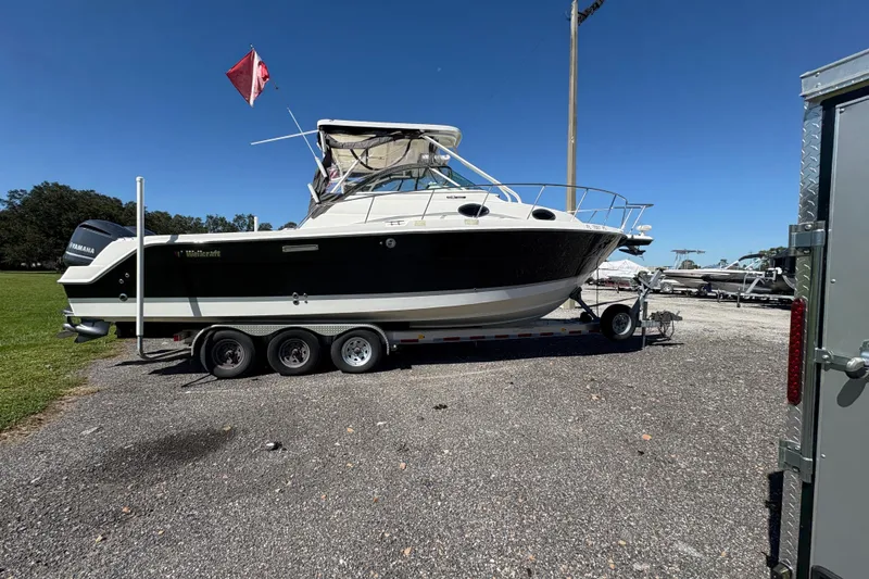 Slide: The Image of 2015 Wellcraft 290 Coastal boat on trailer, parked outdoors under clear blue sky. - 19