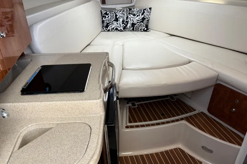 Slide: The Image of 2015 Wellcraft 290 Coastal cabin interior with white seating and wooden flooring. - 32