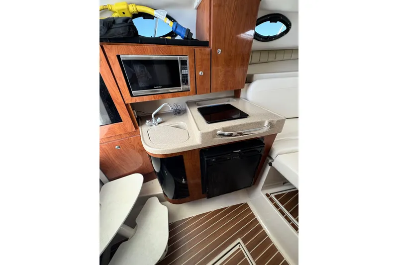 Slide: The Image of 2015 Wellcraft 290 Coastal boat interior with kitchenette, microwave, and wood cabinetry. - 33