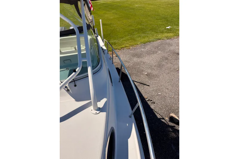 Slide: The Image of 2015 Wellcraft 290 Coastal boat deck with railing, parked on pavement near grass. - 50