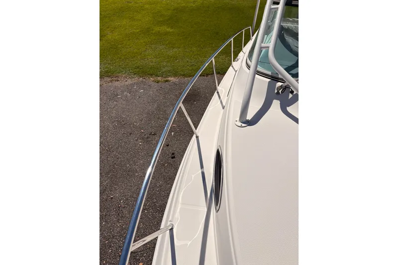 Slide: The Image of 2015 Wellcraft 290 Coastal boat deck with railing, parked on pavement near grass. - 51
