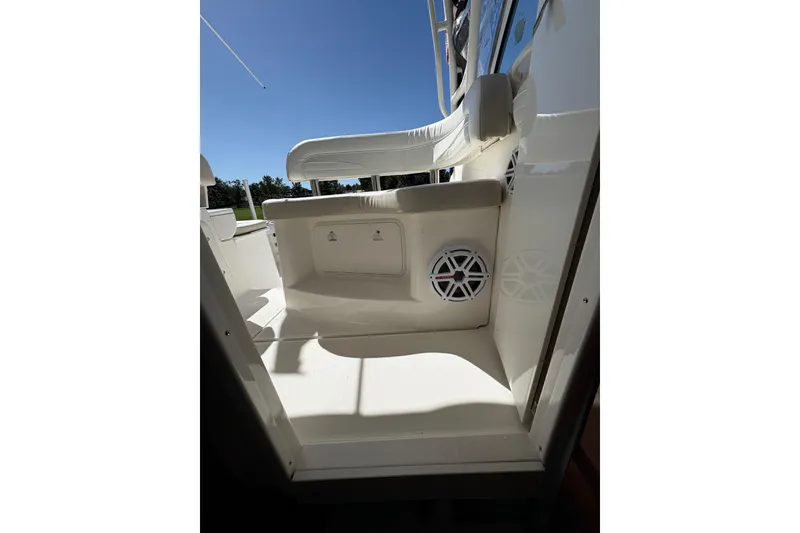 Slide: The Image of 2015 Wellcraft 290 Coastal boat interior with seating and speaker, under clear blue sky. - 56