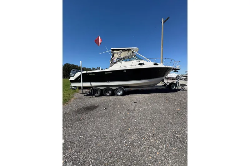 Slide: The Image of 2015 Wellcraft 290 Coastal boat on trailer, parked outdoors under clear blue sky. - 61