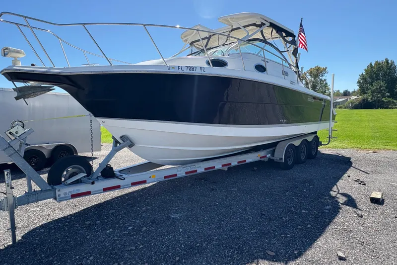Slide: The Image of 2015 Wellcraft 290 Coastal boat on trailer, parked outdoors under clear blue sky. - 62