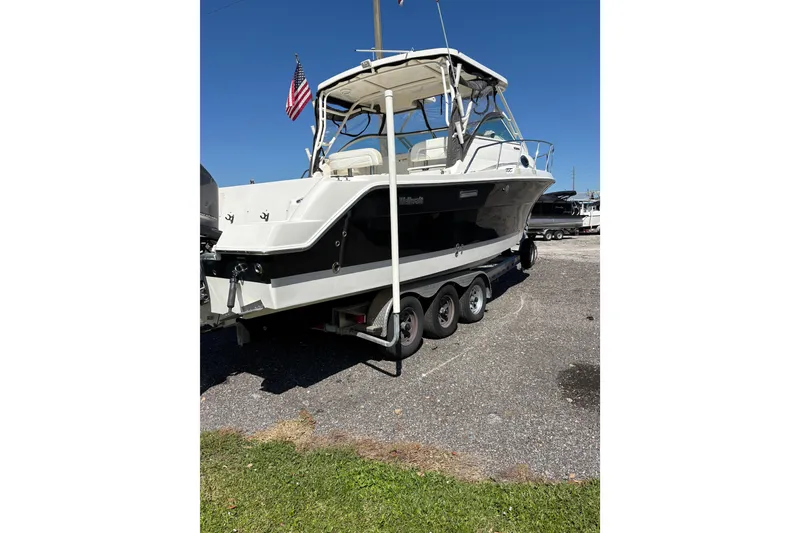 Slide: The Image of 2015 Wellcraft 290 Coastal boat on trailer, parked outdoors under clear blue sky. - 64