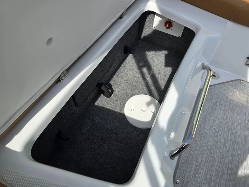 Slide: The Image of 2025 Four Winns H1 boat storage compartment with carpeted interior and metal handle. - 22