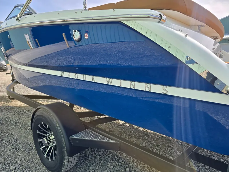 Slide: The Image of 2025 Four Winns H1 boat in vibrant blue on a trailer, side view. - 8