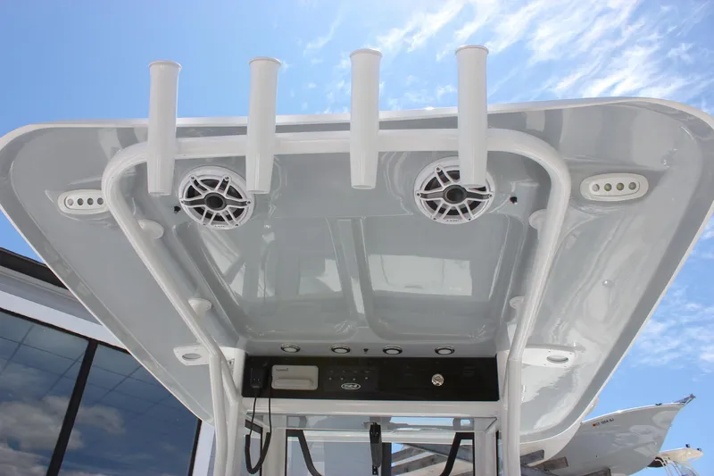 Slide: The Image of T-top of 2026 Sea Hunt Ultra 265 SE boat with rod holders and speakers against blue sky. - 28