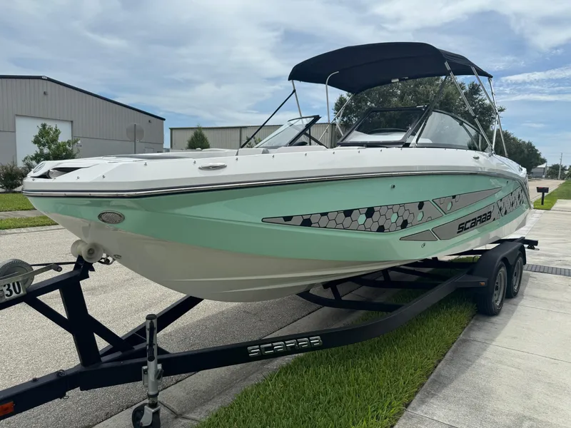 Slide: The Image of 2020 Scarab 255 Open ID boat on trailer, mint green hull, parked outdoors. - 24