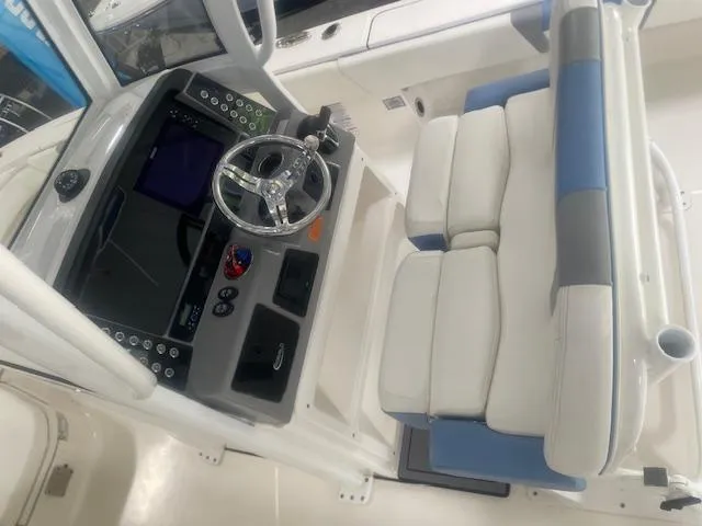 Slide: The Image of 2023 Robalo 266 Cayman boat cockpit with steering wheel and cushioned seating. - 16