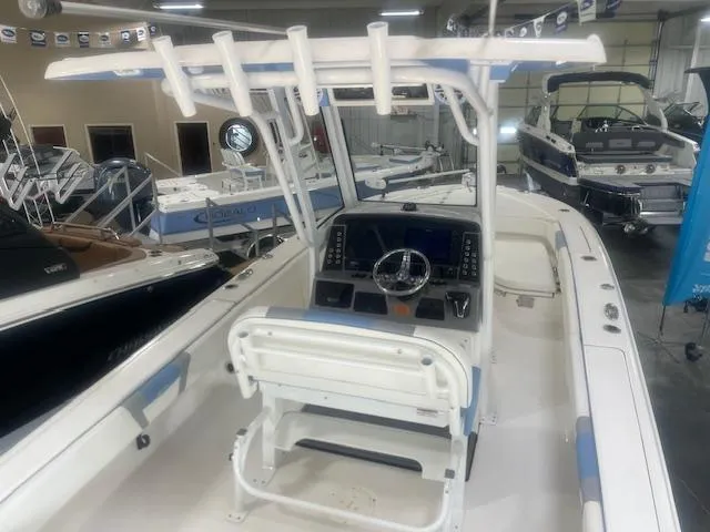 Slide: The Image of 2023 Robalo 266 Cayman boat interior with helm, steering wheel, and seating in showroom. - 7