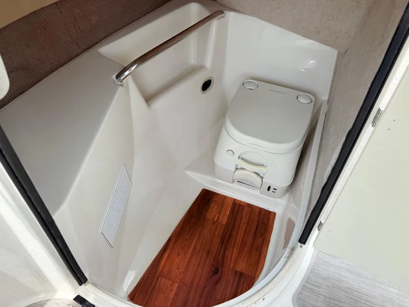 Slide: The Image of 2018 Stingray 214 LR boat interior with compact toilet and wooden flooring. - 17