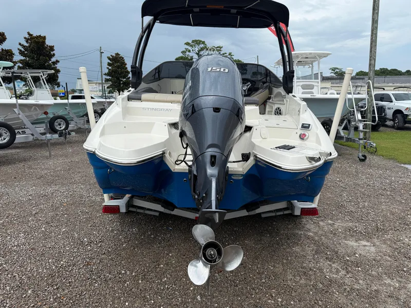 Slide: The Image of 2018 Stingray 214 LR boat with outboard motor, parked on gravel lot. - 5
