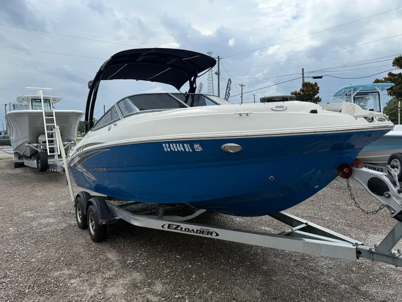 Slide: The Image of 2018 Stingray 214 LR boat on trailer, blue and white, parked outdoors. - 9