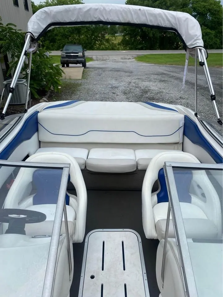 Slide: The Image of 2005 Mariah SX19 boat interior with white and blue seating, parked on gravel. - 6