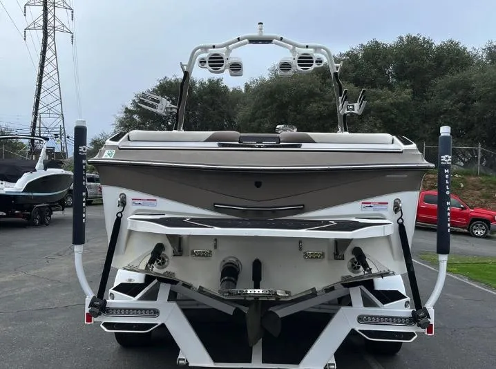 Slide: The Image of 2019 Centurion RI 257 boat, rear view, parked outdoors with trees and vehicles in background. - 3