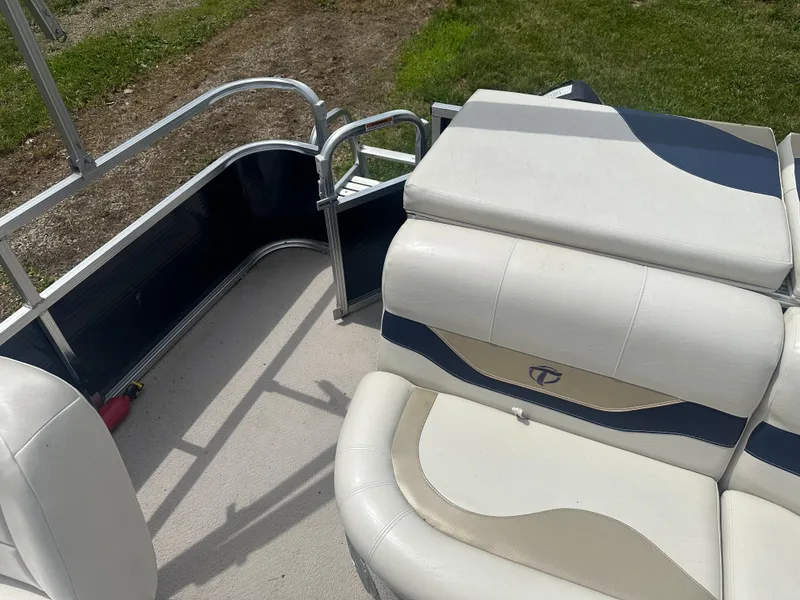 Slide: The Image of 2011 Tahoe LT1900 boat interior with white and blue seating, near grassy area. - 11