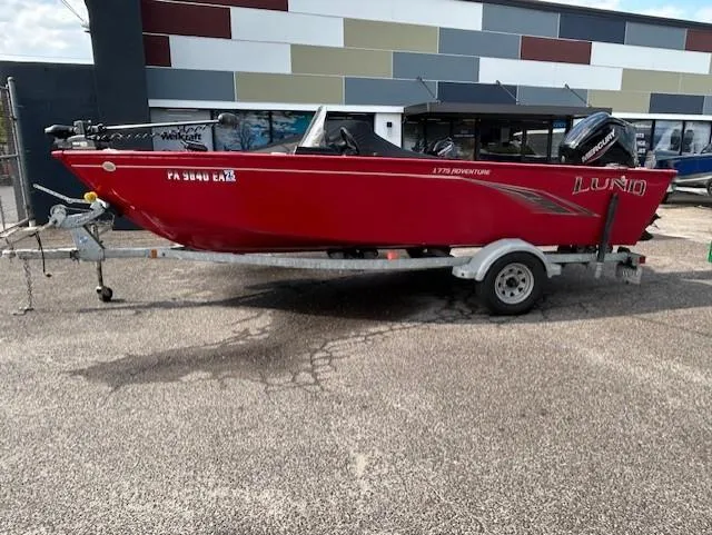 The Image of 2022 Lund 1775 Adventure SS boat on trailer, red exterior, parked outdoors. - 0