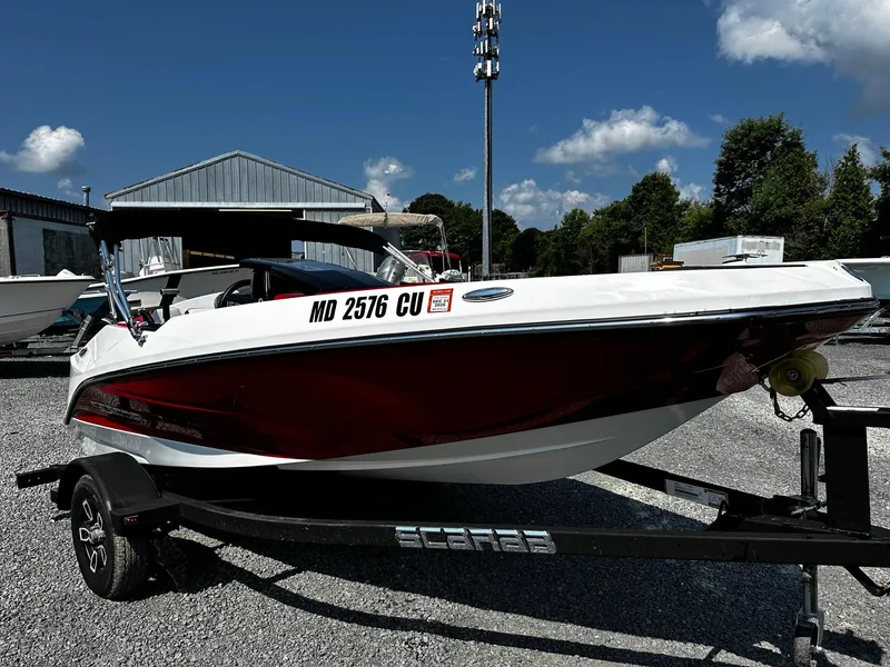 Slide: The Image of 2023 Scarab 165ID Jet Boat on trailer, parked outdoors under blue sky. - 0