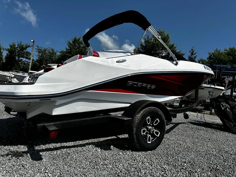 Slide: The Image of 2023 Scarab 165ID Jet Boat on trailer, white and red design, parked outdoors. - 1