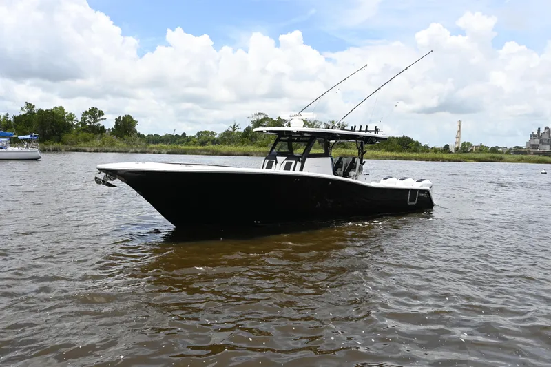 The Image of 2023 Tidewater 380 CC Adventure boat on a calm river under a cloudy sky. - 0
