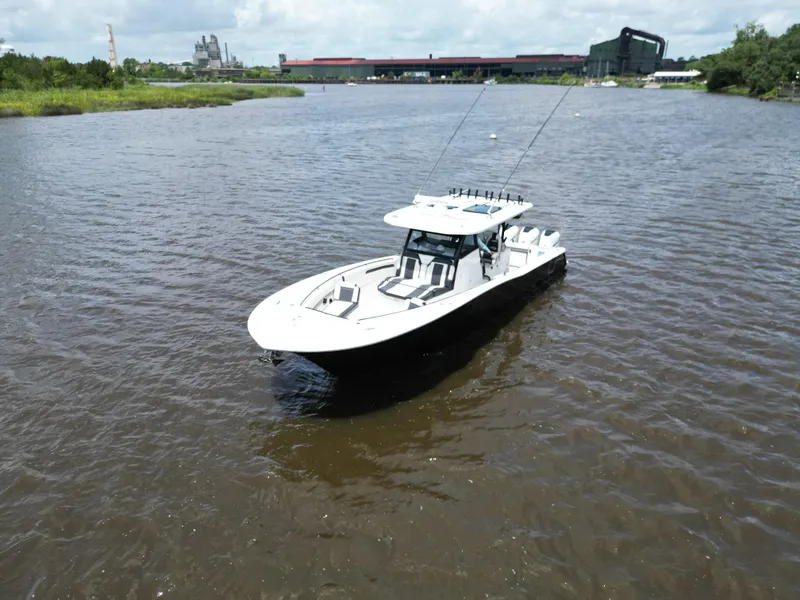 Slide: The Image of 2023 Tidewater 380 CC Adventure boat on a calm river with industrial backdrop. - 4