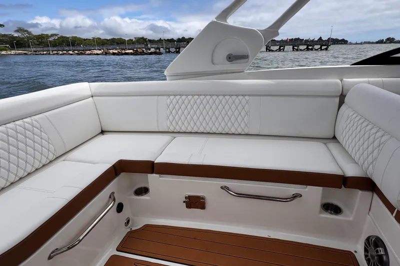 Slide: The Image of 2024 Sea Ray SDX 270 Outboard interior with white cushioned seating and scenic water view. - 4