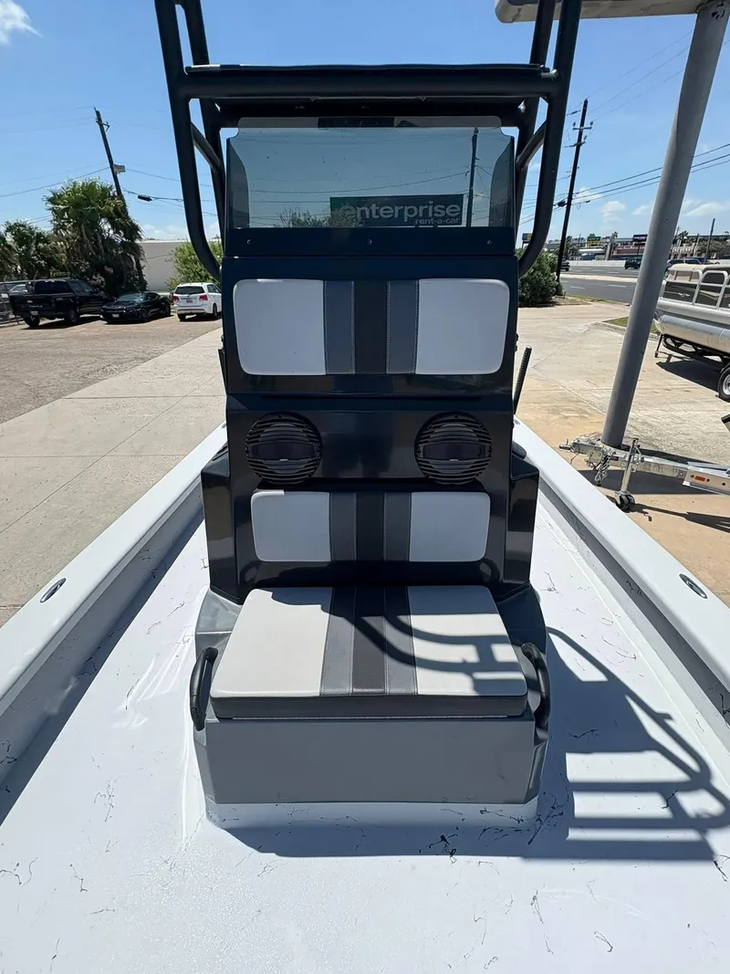 Slide: The Image of 2022 JH Performance Outlaw 250 boat interior with seating and speakers, parked outdoors. - 9