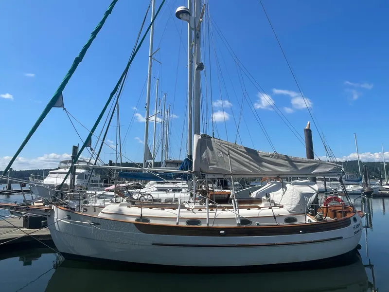 The Image of 1985 Hans Christian 33T sailboat docked in a marina under a clear blue sky. - 0