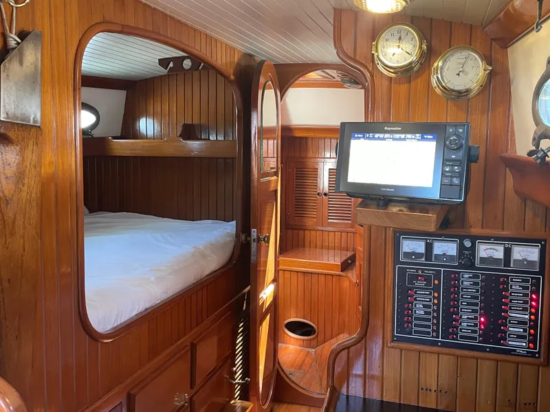Slide: The Image of Interior of 1985 Hans Christian 33T sailboat with wood paneling, bed, and navigation equipment. - 10