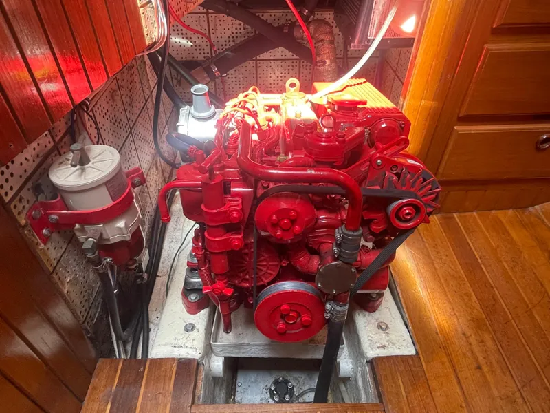 Slide: The Image of Red engine inside a 1985 Hans Christian 33T boat, surrounded by wooden paneling. - 14