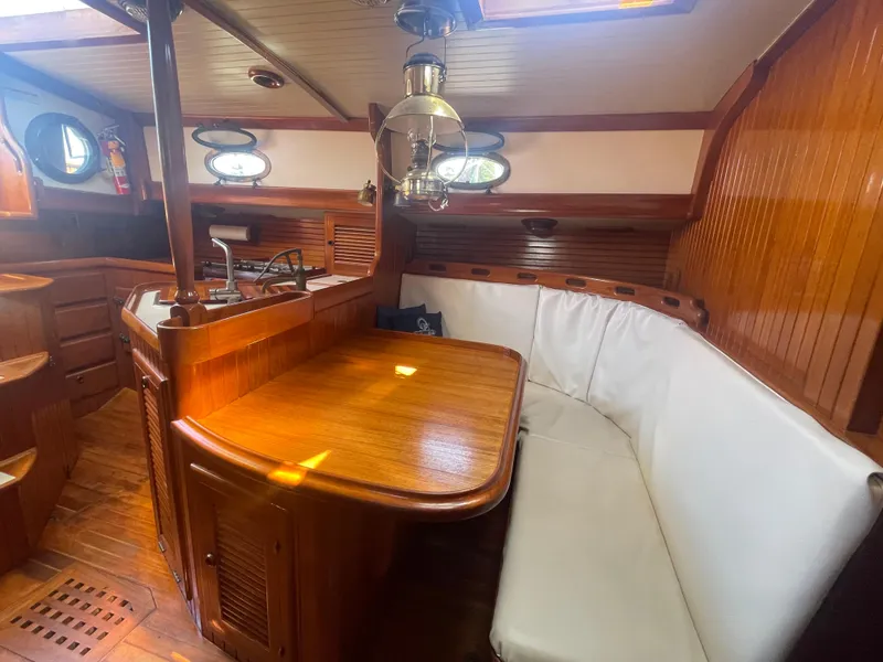 Slide: The Image of Interior of 1985 Hans Christian 33T sailboat with wooden dining area and white cushioned seating. - 27