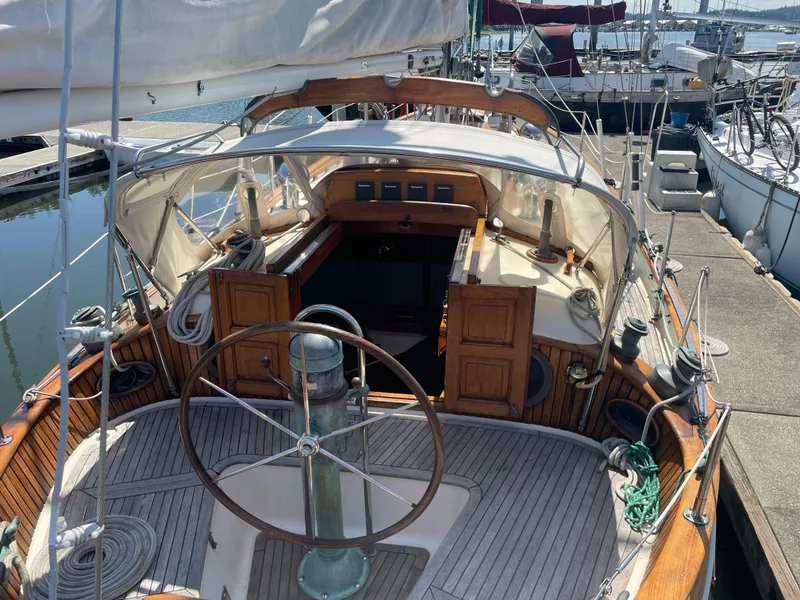 Slide: The Image of 1985 Hans Christian 33T sailboat cockpit with wooden details and steering wheel at marina. - 4