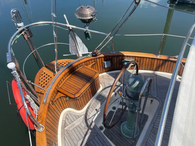 Slide: The Image of 1985 Hans Christian 33T sailboat cockpit with wooden wheel and deck, docked on calm water. - 7