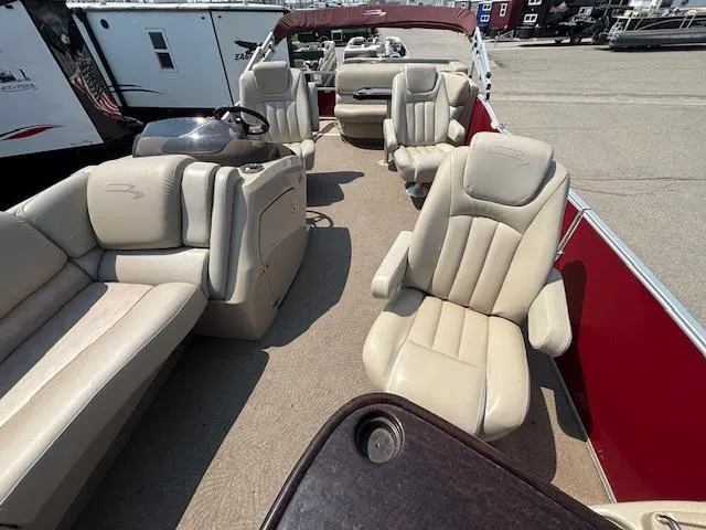 Slide: The Image of 2012 Bennington R25 pontoon boat interior with beige seating and red accents. - 11