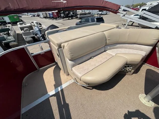 Slide: The Image of 2012 Bennington R25 pontoon boat with beige seating and red accents, parked in a marina. - 16